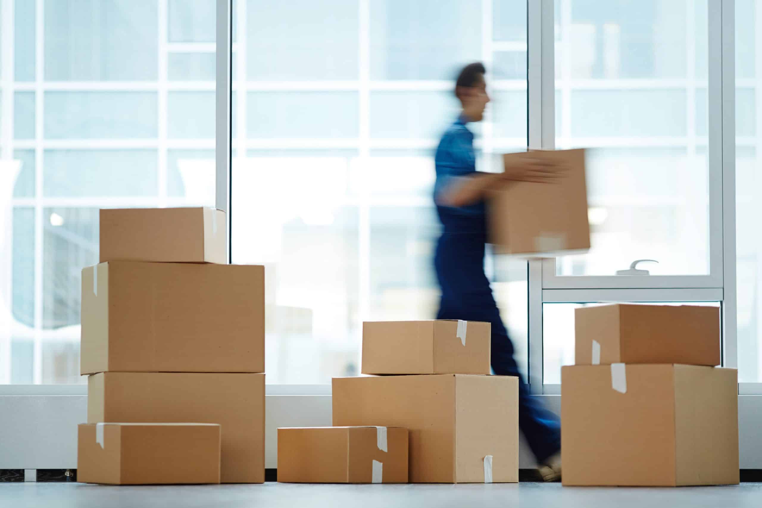 Blurred motion of contemporary worker with packed box walking to new office