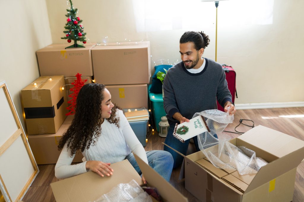 young couple wrapping christmas decorations in bubble wrap