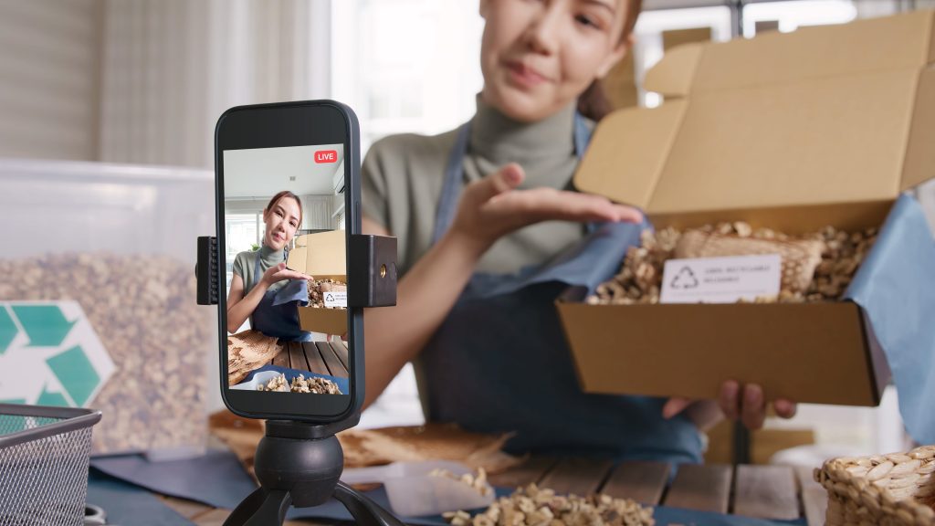 SME owner live stream talk on phone showing eco care plastic free packaging box
