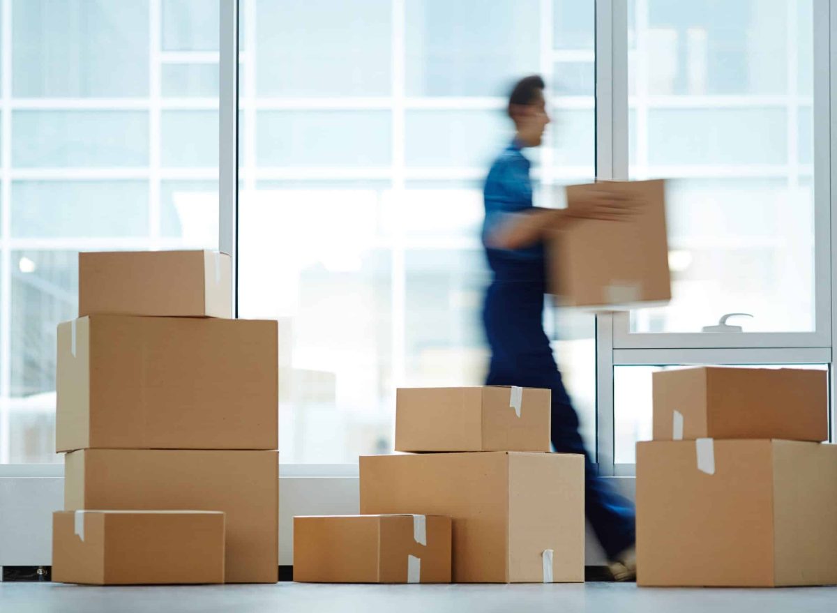 Blurred motion of contemporary worker with packed box walking to new office