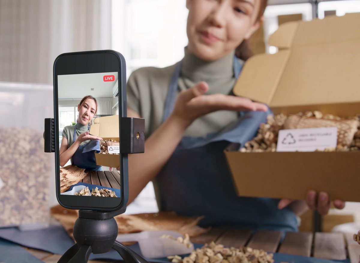 SME owner live stream talk on phone showing eco care plastic free packaging box