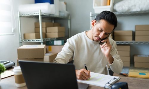 Latin Entrepreneur Taking Notes While Talking On The Phone With